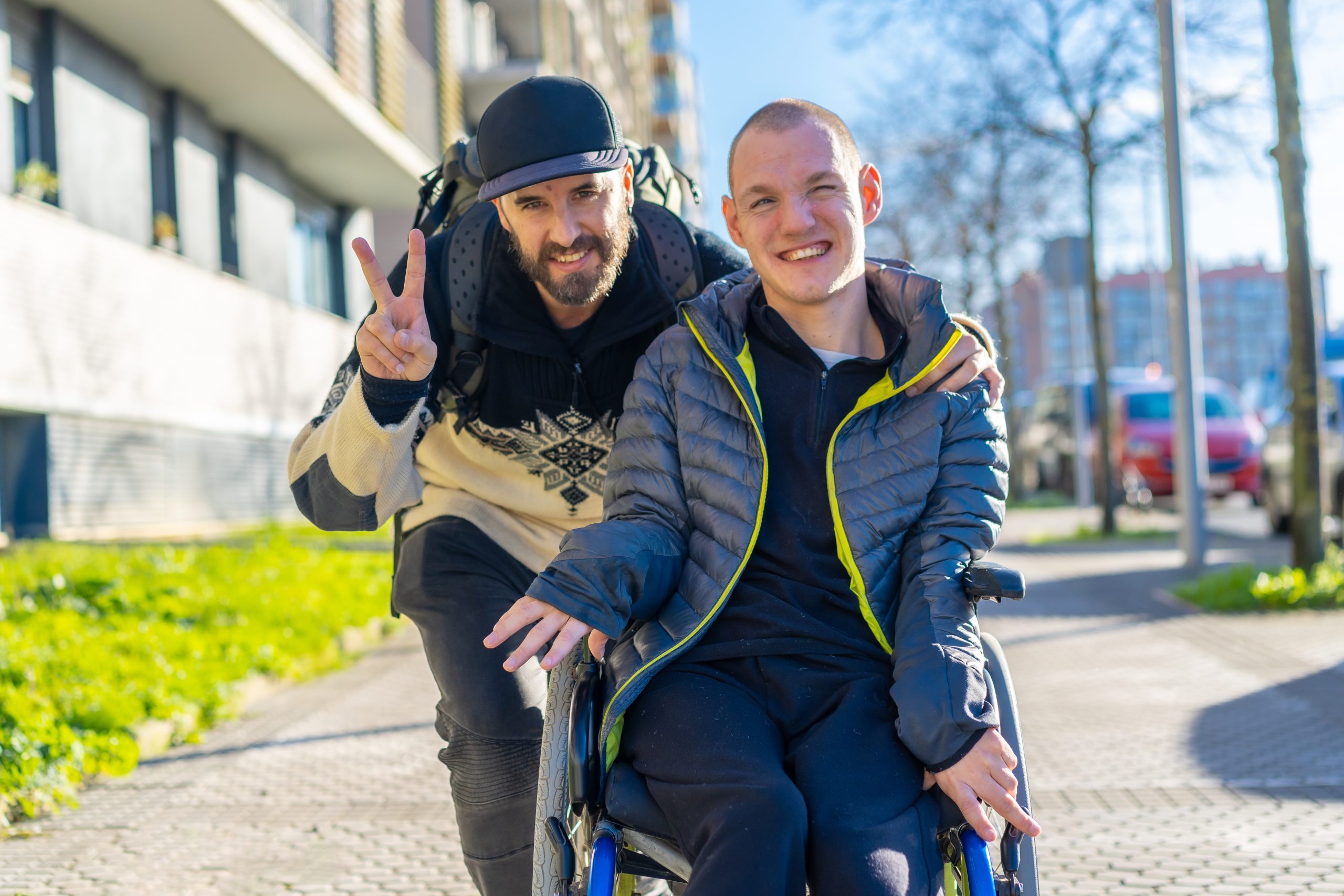 A man standing next to a friend in a wheelchair