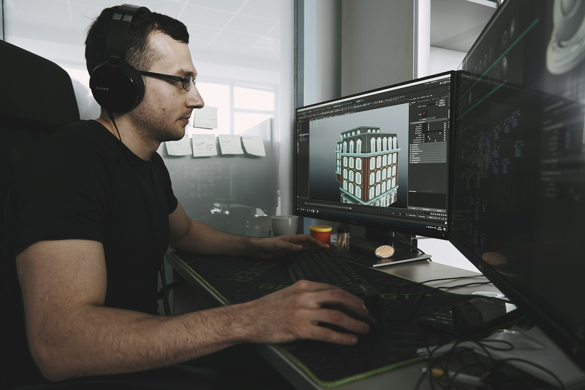 Designer working on a 3D building model across two monitors